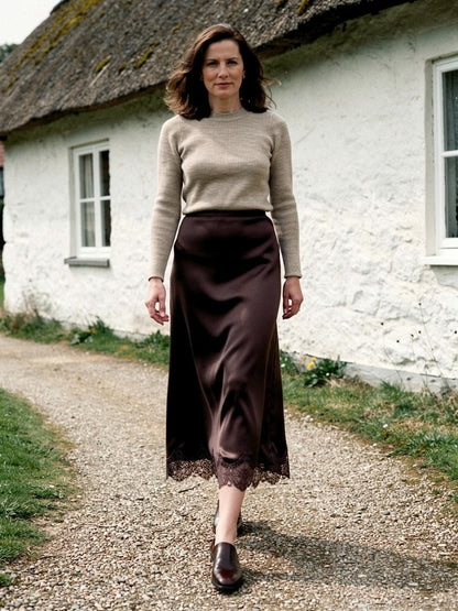 Satin midi skirt with a scalloped lace hem in Sable, worn on a country path