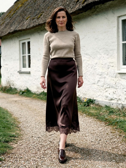 Satin midi skirt with a scalloped lace hem in Sable, worn on a country path