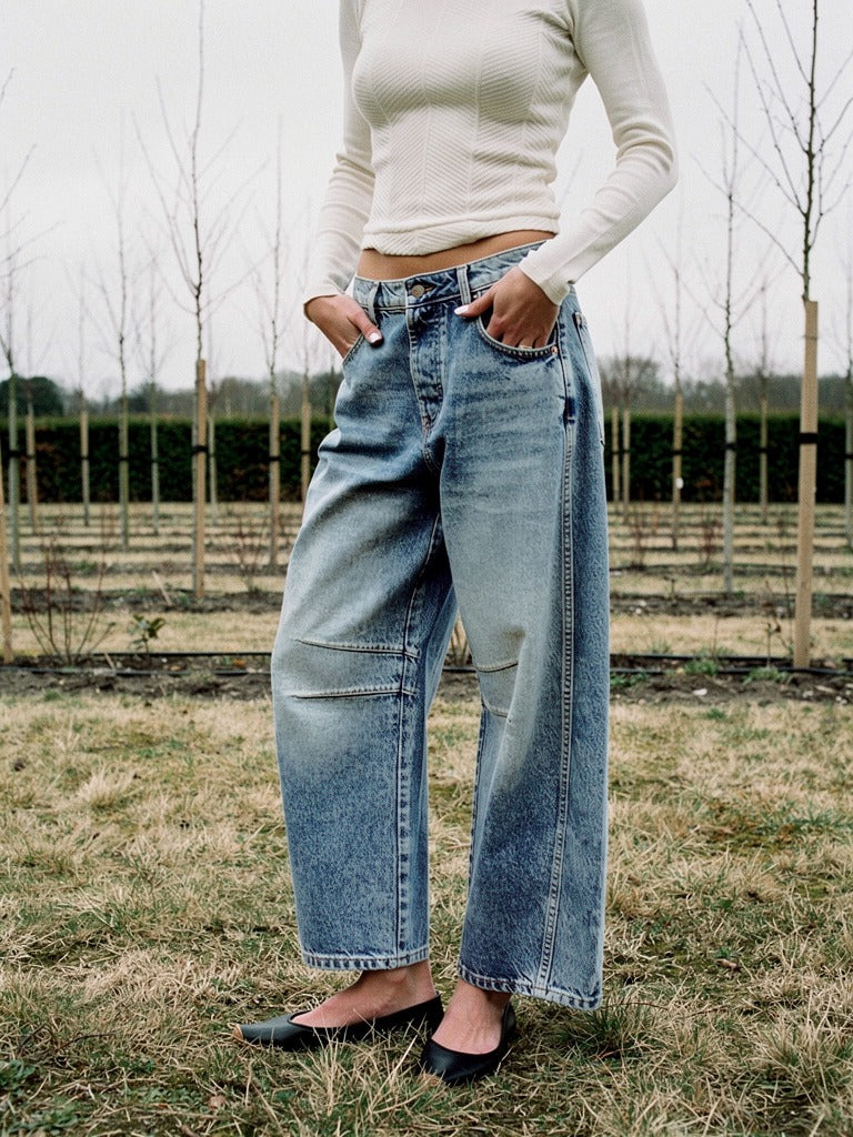 Womens barrel jeans in Vintage Blue denim worn on a grass track in an English tree nursery in winter