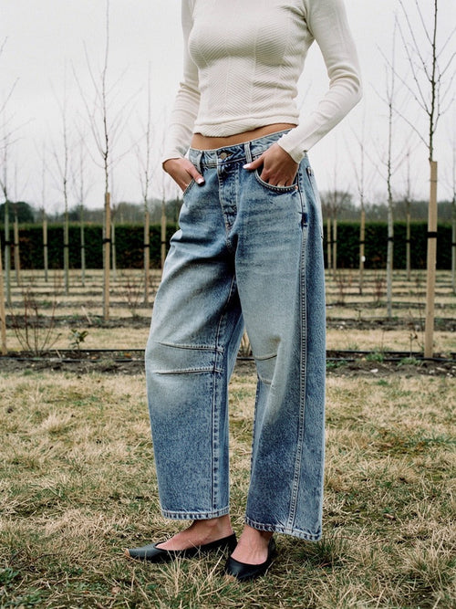Womens barrel jeans in Vintage Blue denim worn on a grass track in an English tree nursery in winter