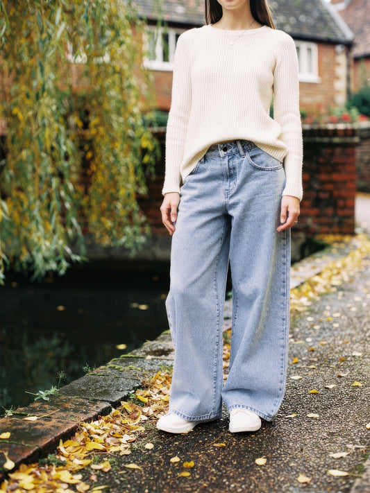 Womens high-rise wide-leg jeans in Bleach Blue stonewashed denim, worn by a village pond in autumn