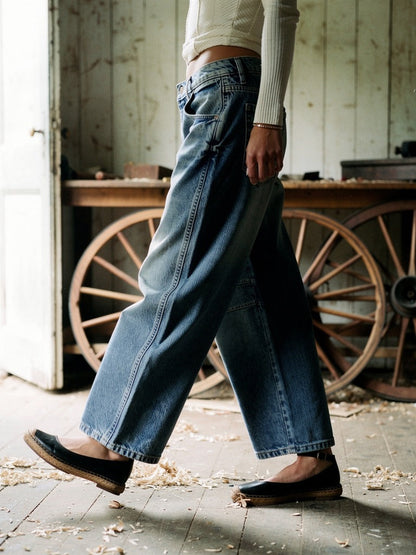 Side profile of the Vintage Blue barrel jeans walking through an English wheelwrights workshop