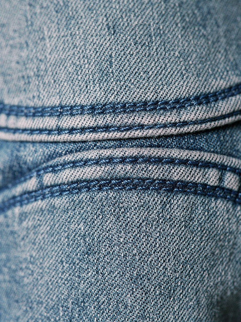 Close detail of the two curved knee seams and the vintage washed denim of the Lechlade barrel jeans