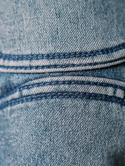 Close detail of the two curved knee seams and the vintage washed denim of the Lechlade barrel jeans