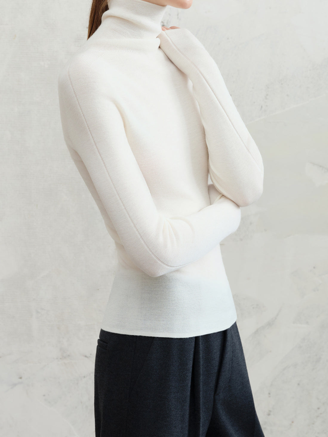 Womens wool roll neck top in vellum white worn with dark wool trousers