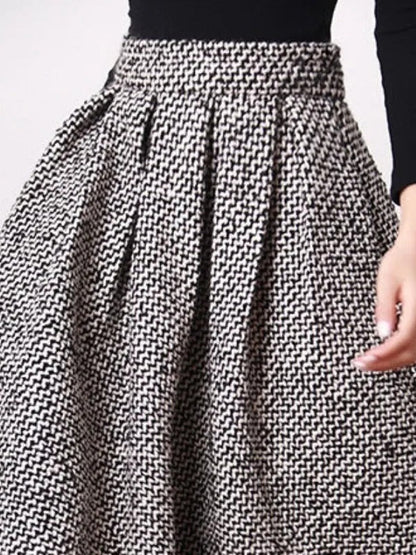Black and white herringbone A line skirt seen from the front, with a hand slipped into the side pocket