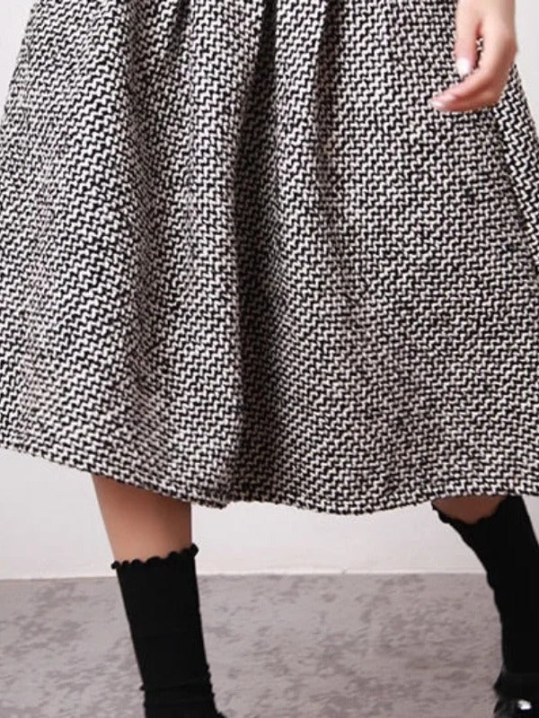 Hem of the black and white herringbone A line skirt on the model, showing the knee length above mid calf socks