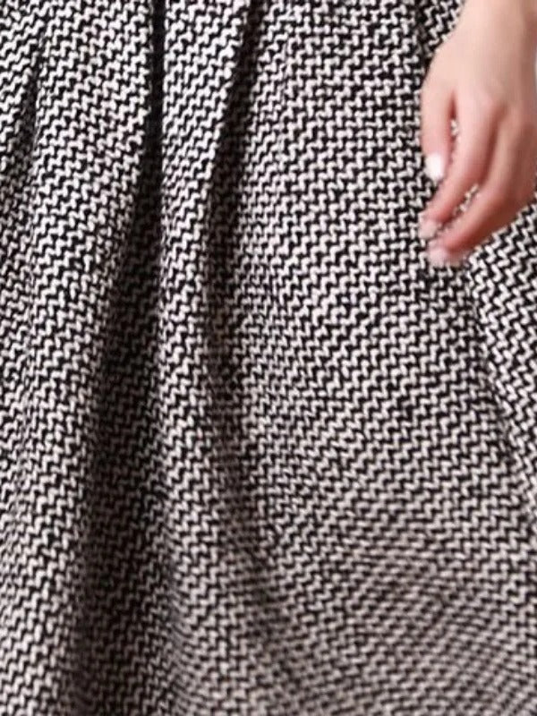 Side pocket and woven herringbone cloth of the black and white A line skirt seen close up