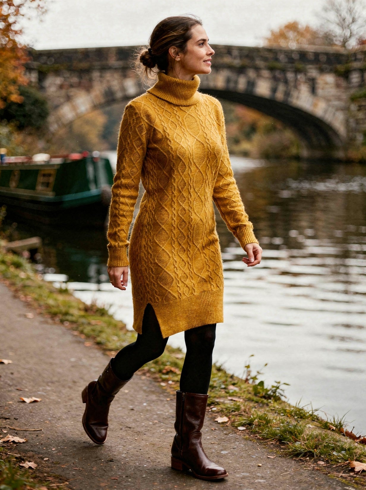 Woman walking along a canal towpath in the mustard Aran cable-knit polo-neck jumper dress