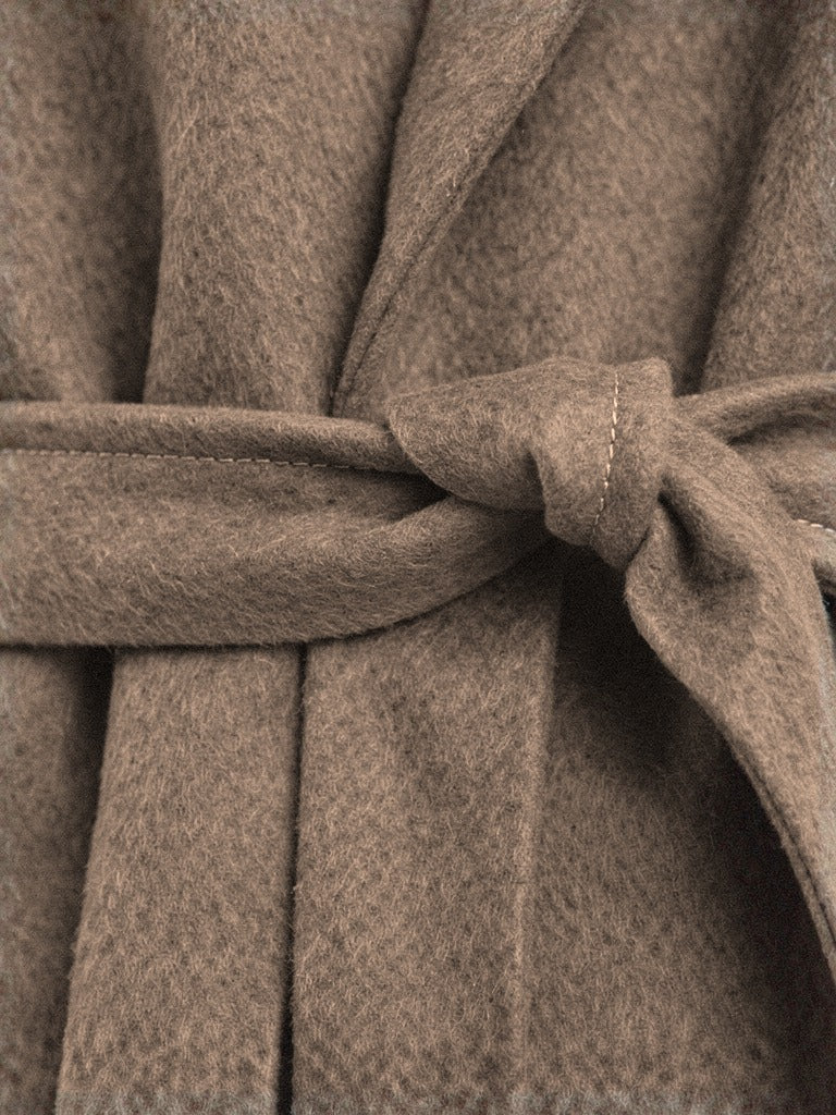 Close up of the brushed soft touch cloth of the belted wrap coat at the knot of the self tie belt