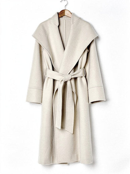 Belted wrap coat in Bisque cream on a wooden hanger, showing the deep shawl collar and the tied belt