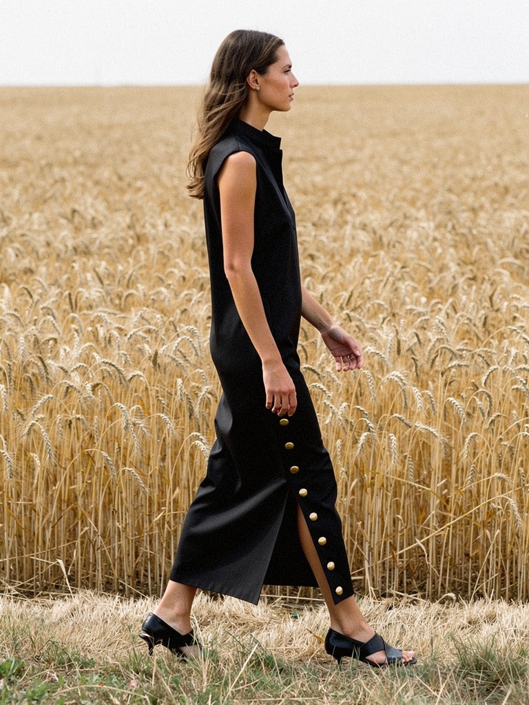 Black column dress seen in profile, the side split open as she walks