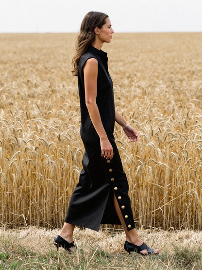 Black column dress seen in profile, the side split open as she walks