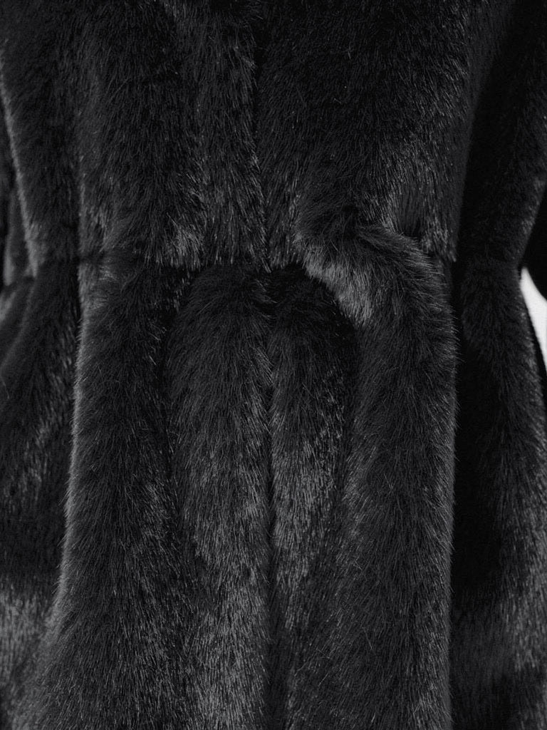 Close up of the dense black faux fur pile of the coat, gathered into soft folds at the waist