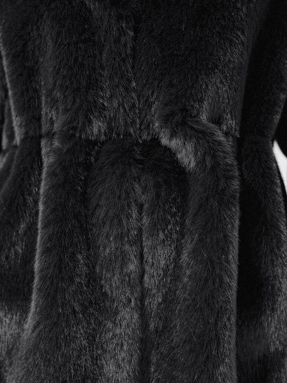 Close up of the dense black faux fur pile of the coat, gathered into soft folds at the waist