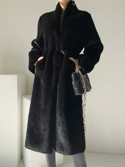 Black fluffy coat worn closed with hands in the pockets, seen from the front in the studio