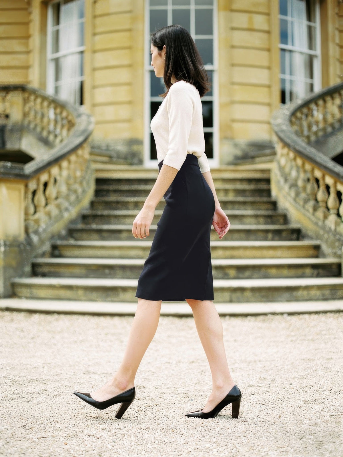 Black pencil skirt worn with a cream knit and court shoes on a country house staircase, Aylworth by Harlbury