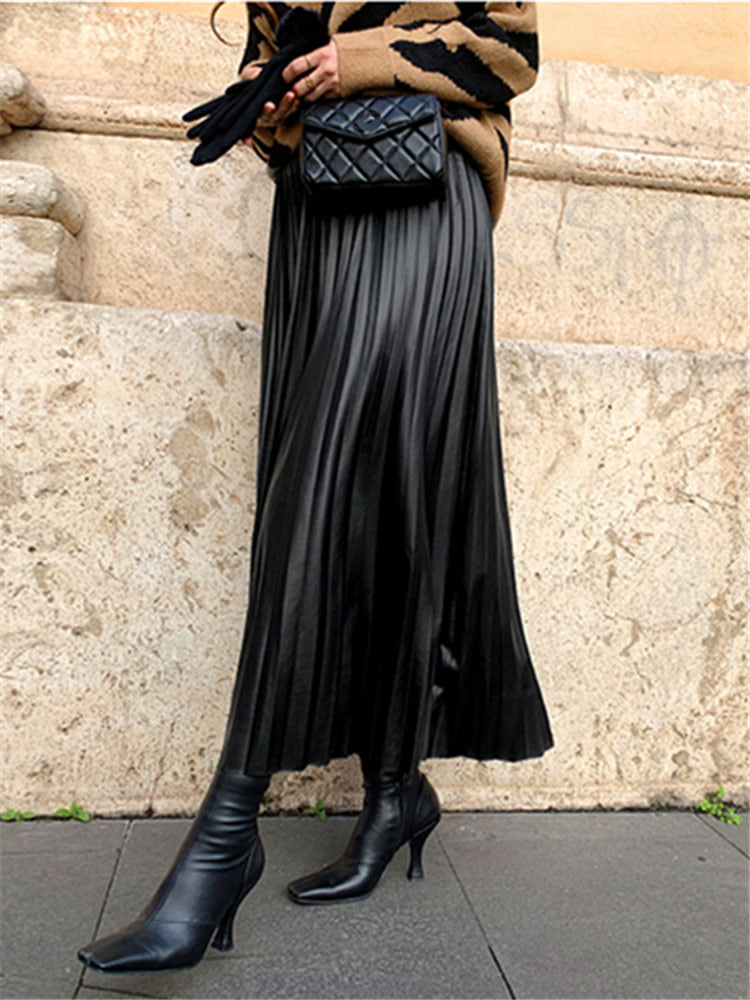 Supplier photograph of the black pleated skirt worn in the street, showing the full length of the skirt and the pointed pleated hem
