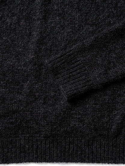 Close-up of the fine-gauge black knit, ribbed cuff and hem of the roll neck jumper