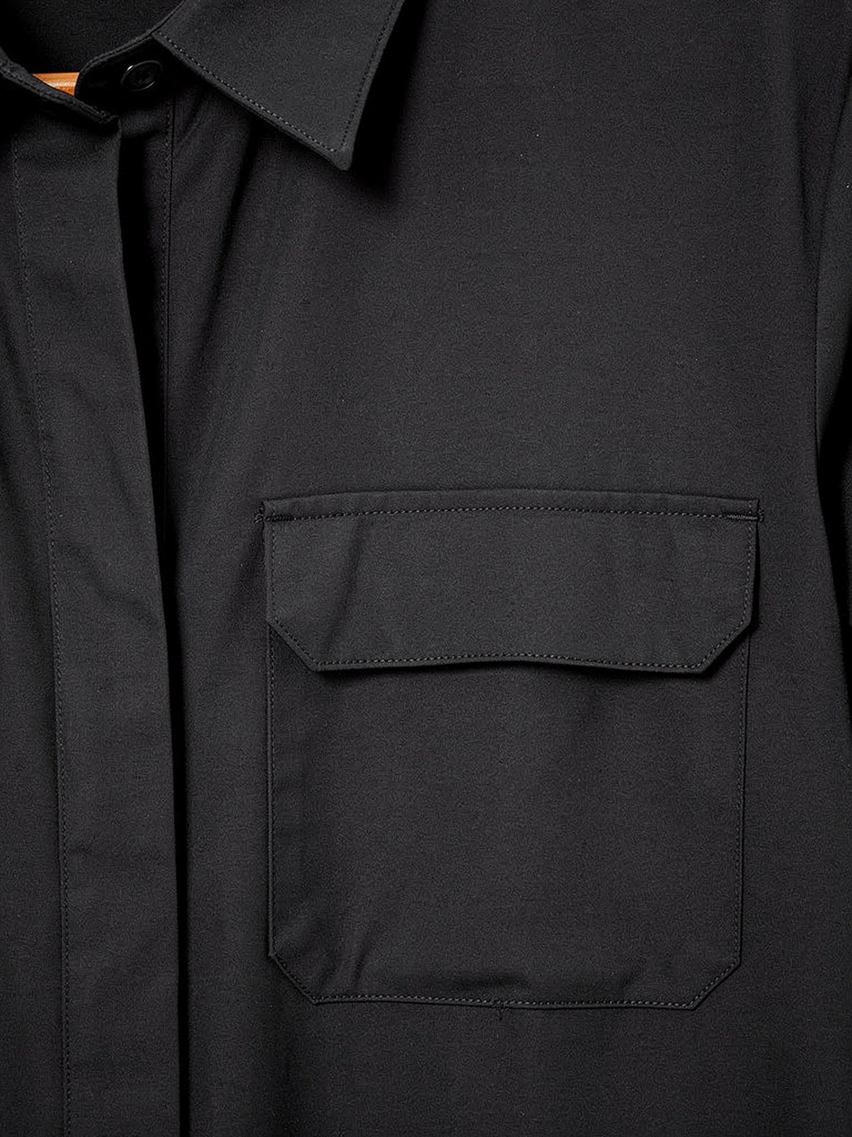 Close-up of the matte woven cloth, collar and flap chest pocket of the black shirt dress