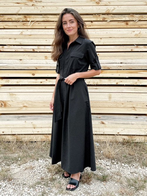 Woman wearing a black short sleeve shirt dress, front view, full length