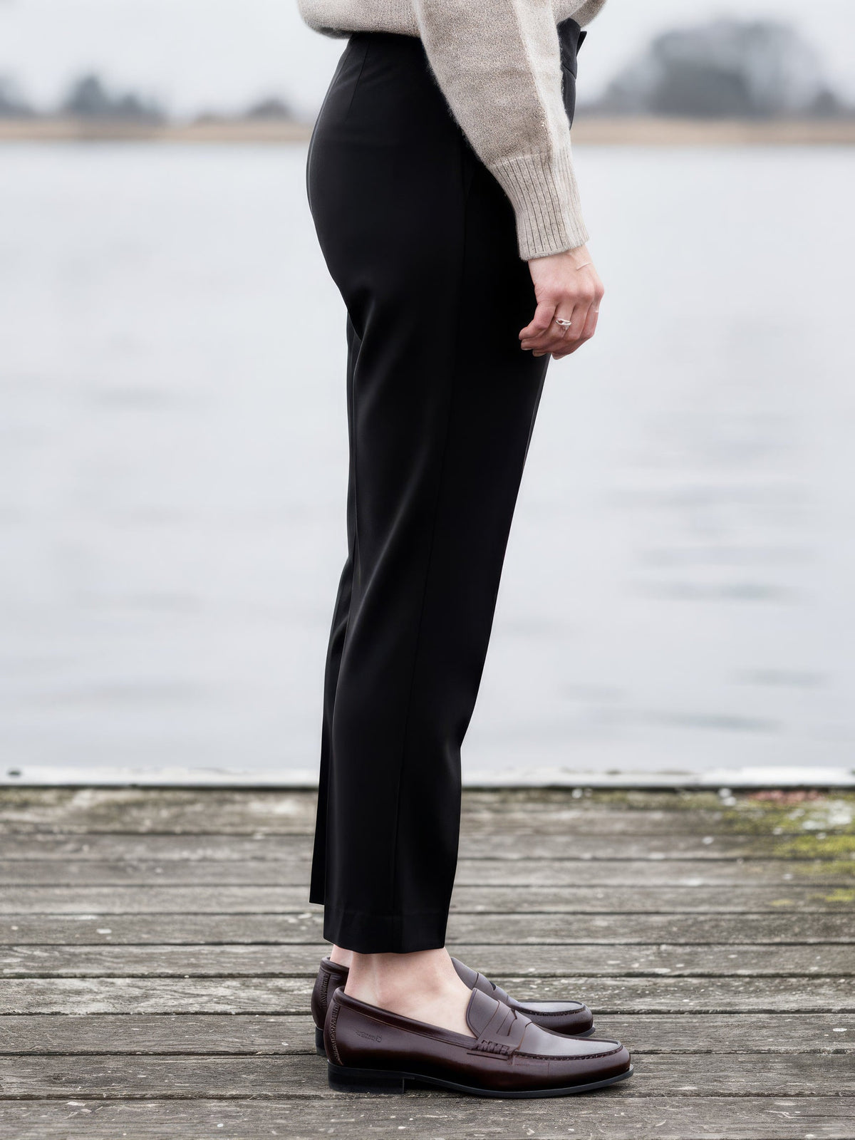Side view of the black high-rise trousers, showing the cigarette leg over a loafer