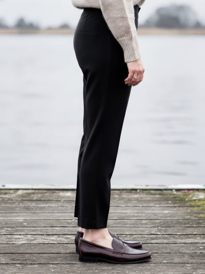 Side view of the black high-rise trousers, showing the cigarette leg over a loafer