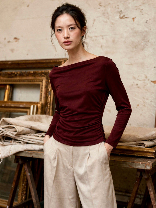 Burgundy boat neck top worn with cream wide leg trousers in a country auction room