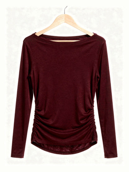 Burgundy boat neck top on a hanger showing the wide slash neckline and the ruched side seams