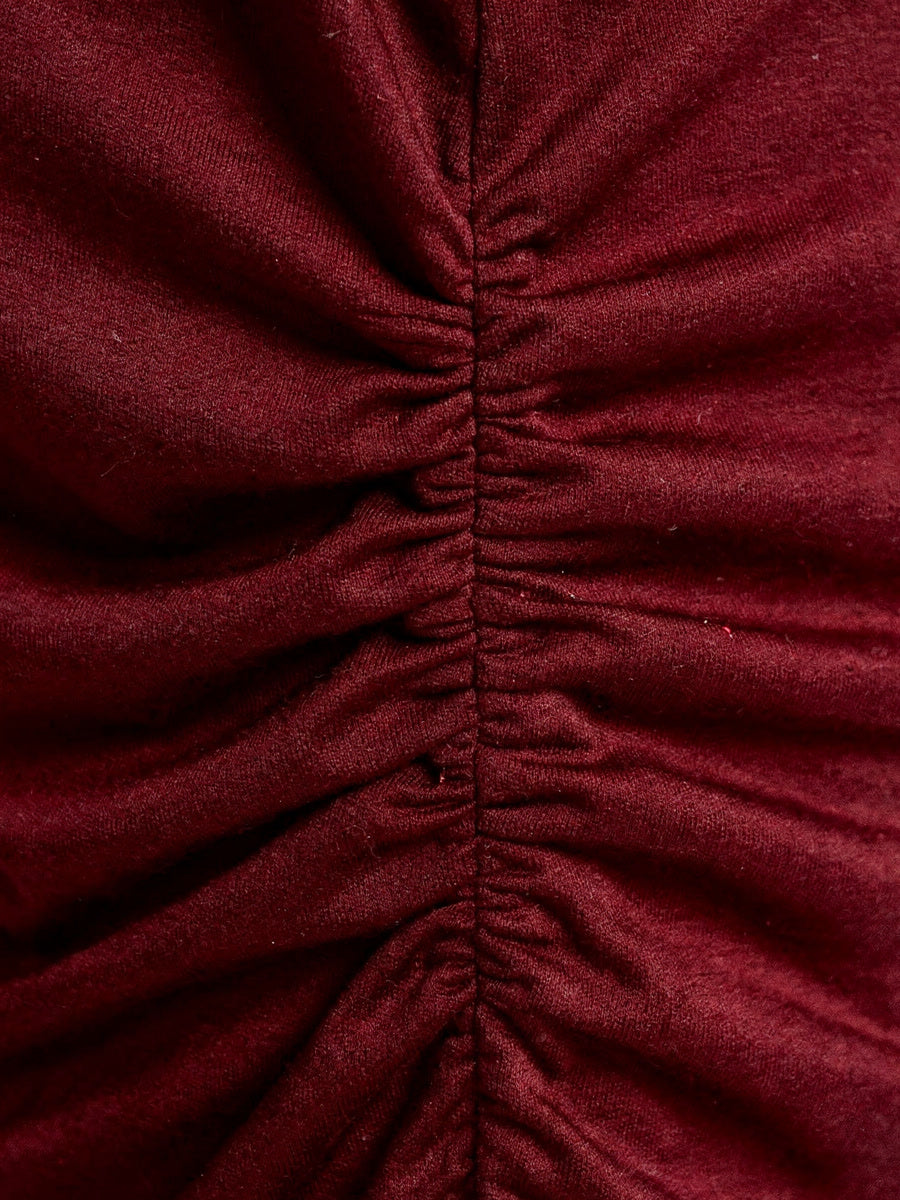 Close view of the ruched side seam and the fine stretch jersey of the burgundy boat neck top