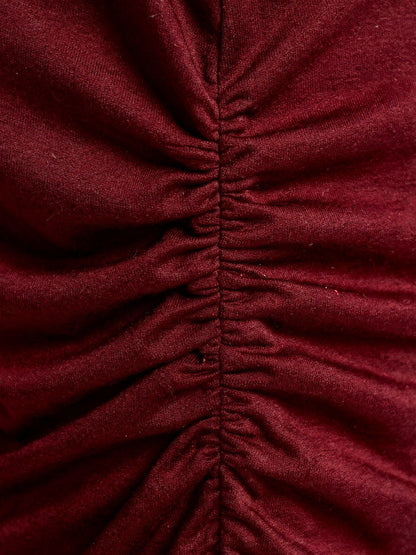 Close view of the ruched side seam and the fine stretch jersey of the burgundy boat neck top