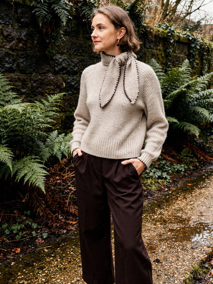 Bow neck jumper in Cashew worn with chocolate wide-leg trousers in a Victorian fernery