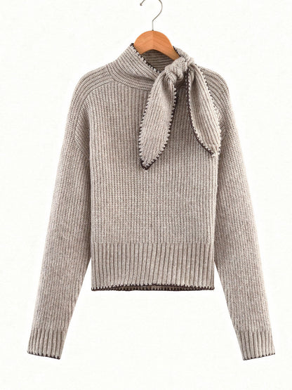 Bow neck jumper in Cashew on a wooden hanger, stand collar and knitted tie in a bow