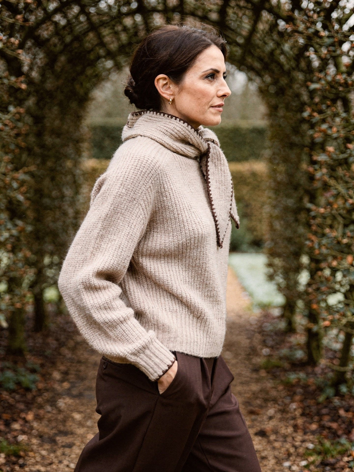 Side view of the bow neck jumper in Cashew, showing the stand collar and the short ribbed hem