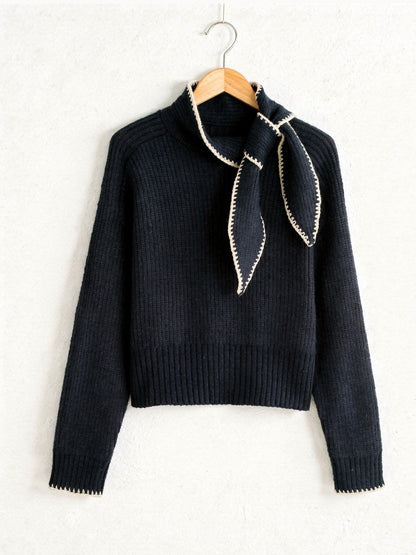 Bow neck jumper in Fathom Navy with cream contrast whipstitch, on a wooden hanger