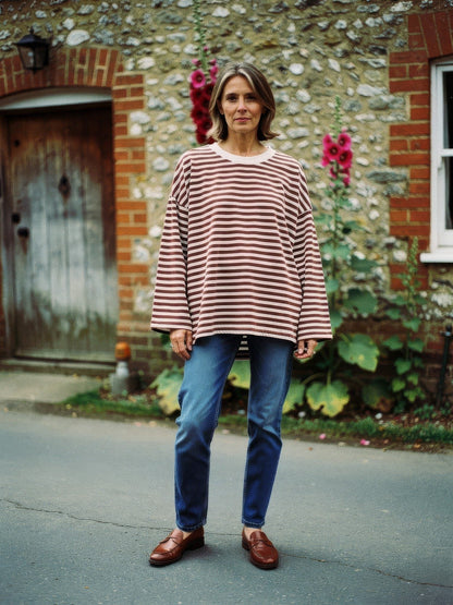 Woman wearing an oversized cocoa brown breton stripe top with jeans in an English village lane