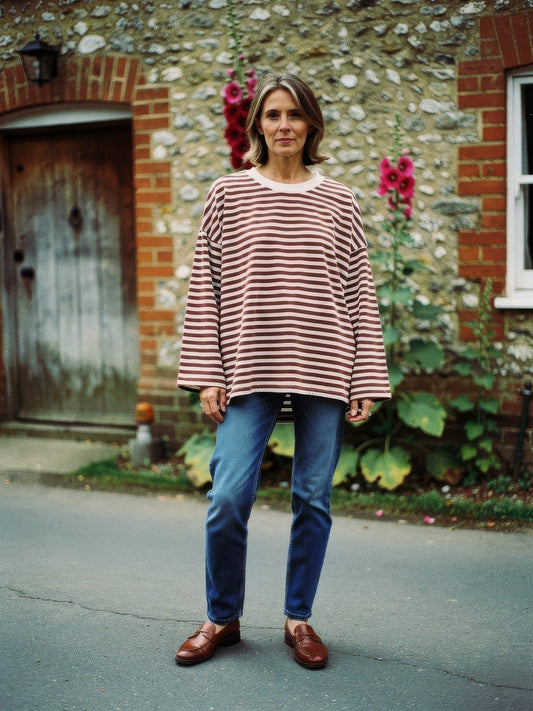 Woman wearing an oversized cocoa brown breton stripe top with jeans in an English village lane
