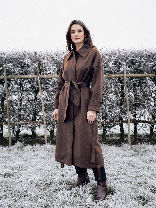 Brown coat in Carob, belted and worn long on a frosted winter morning