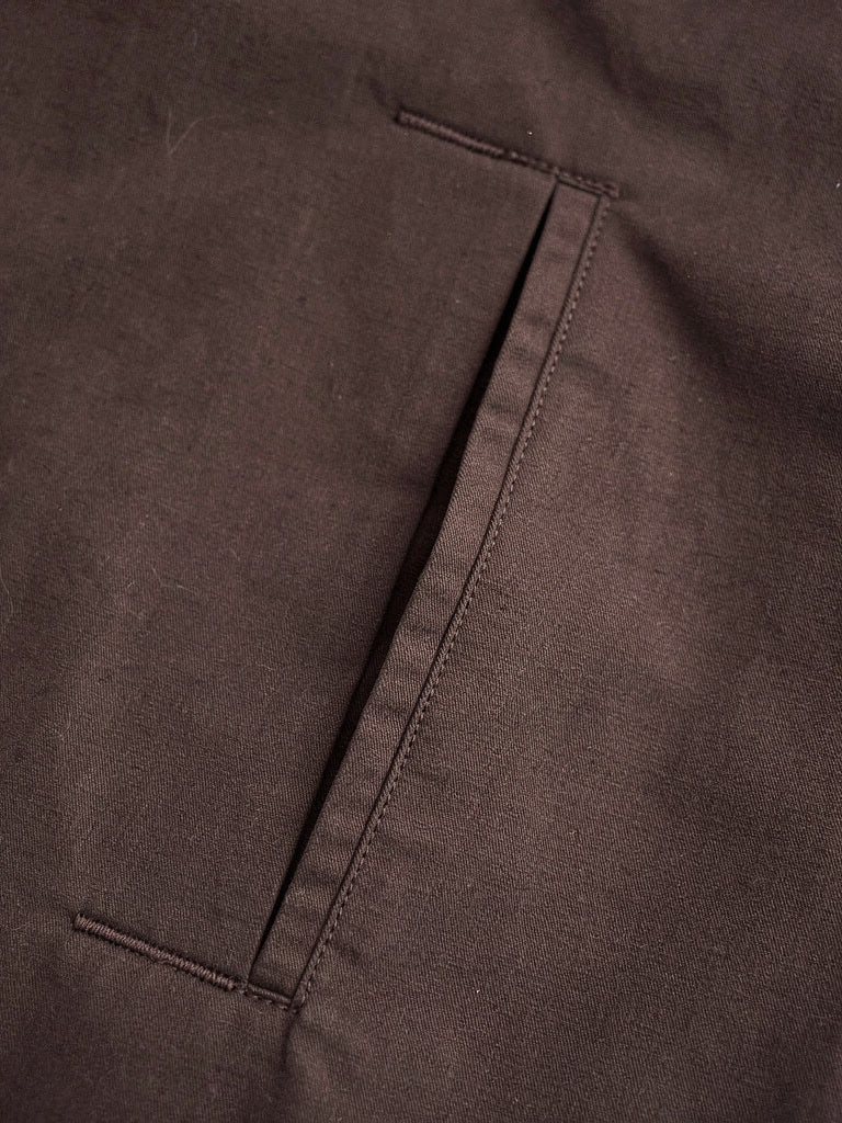 Close up of the cotton blend cloth and slanted welt pocket of the brown coat