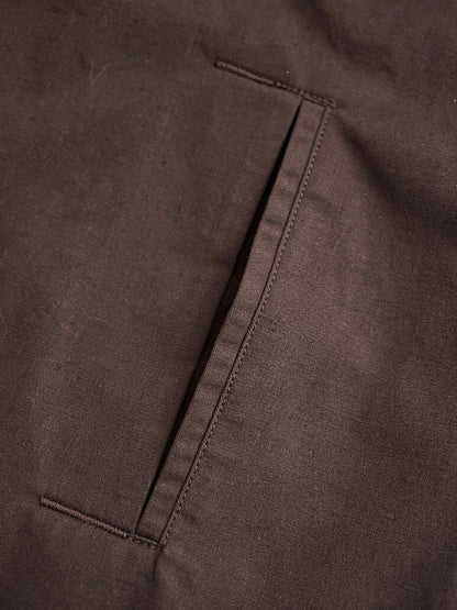 Close up of the cotton blend cloth and slanted welt pocket of the brown coat