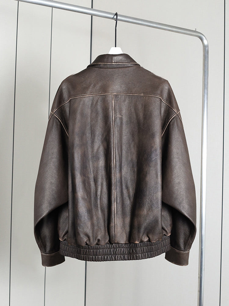 Brown distressed faux leather bomber jacket seen from the back on a hanger, in Bison
