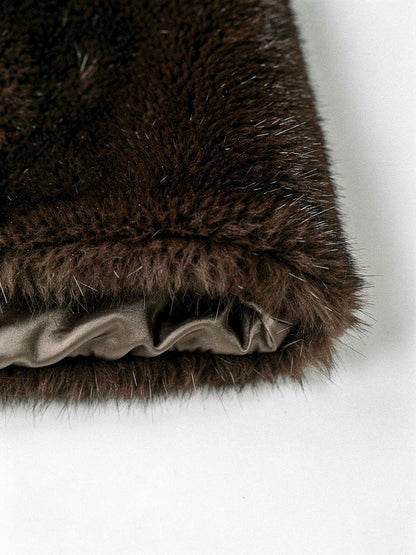 Close up of the dense plush pile and the taupe satin lining of the brown faux fur coat