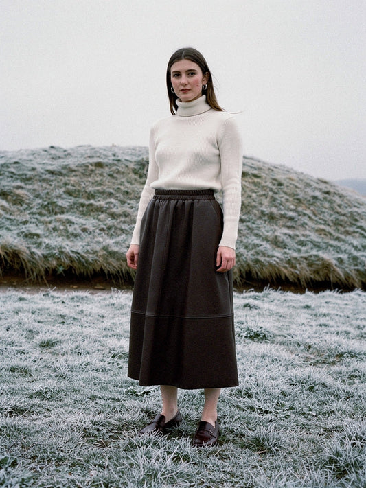 Brown faux leather skirt worn with a cream roll neck on a frosted English chalk down, the A line hem falling to the middle of the calf
