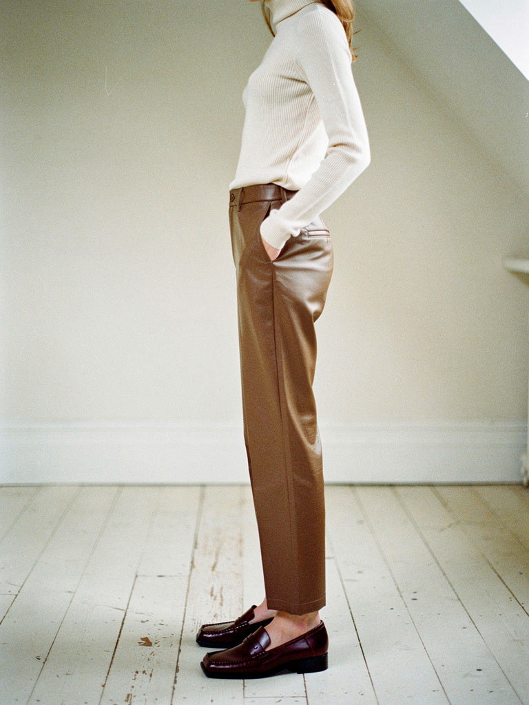 Brown faux leather trousers in Toffee seen in profile with loafers