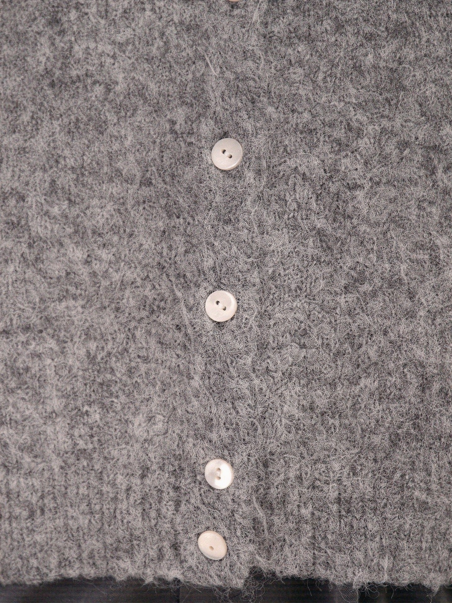Close-up of the brushed knit fabric and pearlised button of the cardigan