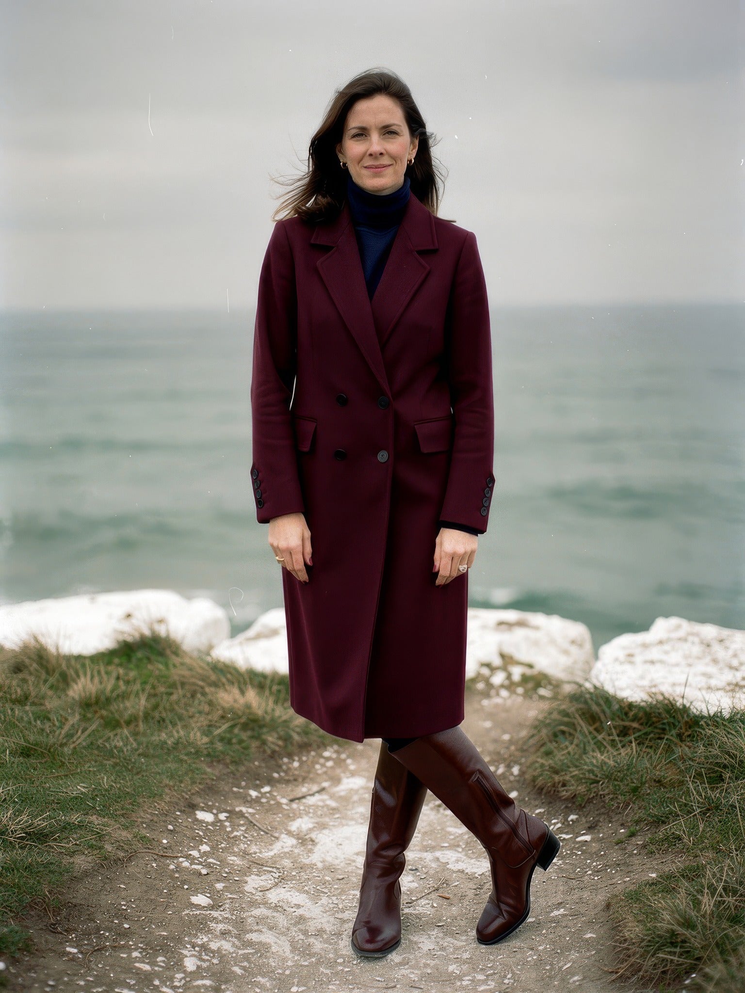 Womens burgundy coat worn buttoned on a chalk clifftop path, double-breasted longline, in Claret
