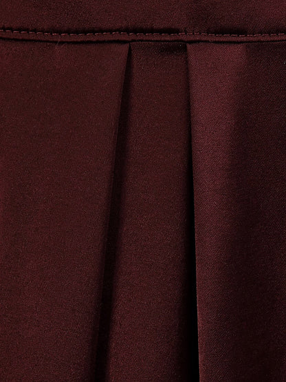 Close up of the plain satin cloth and hem of the burgundy dress in Claret