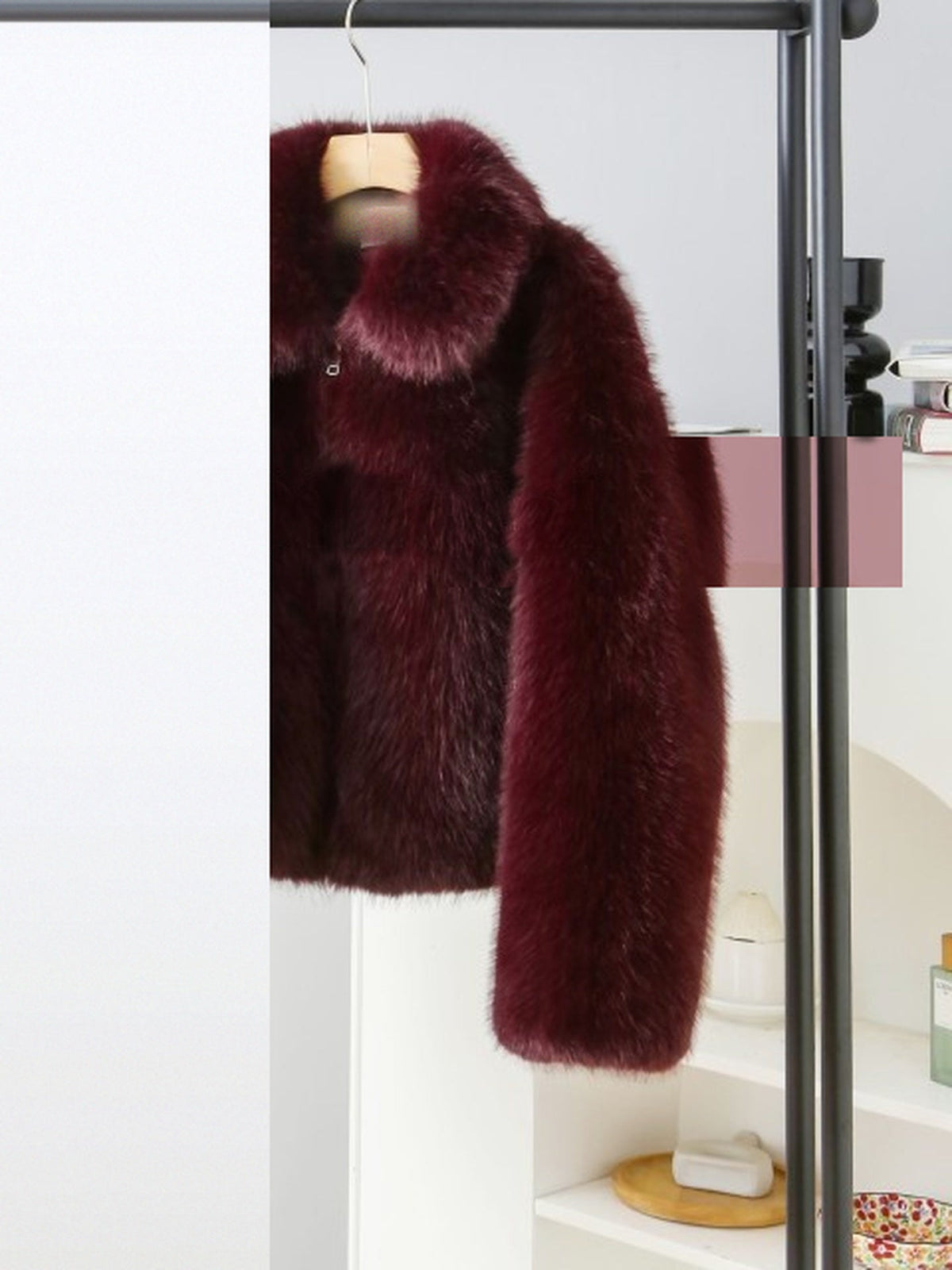 Burgundy faux fur jacket hanging on a rail, photographed by the maker