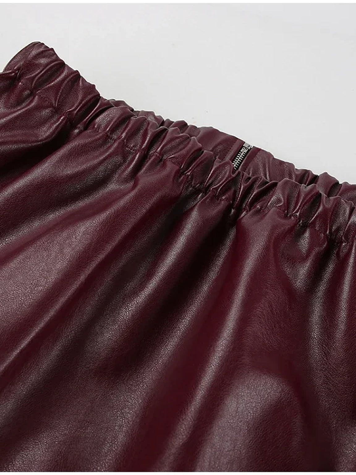 Elasticated gathered hem of the burgundy faux leather jacket
