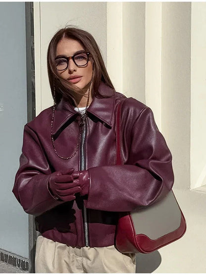 Burgundy faux leather jacket styled with cream trousers